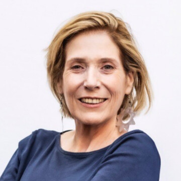 Headshot of white woman with short blonde hair wearing a dark blue top, looking at the camera and smiling