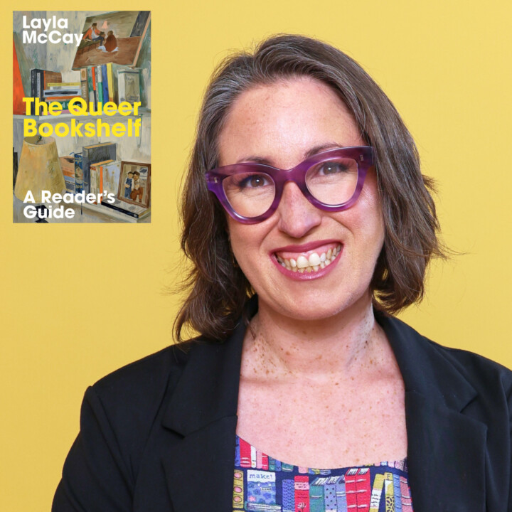 A white woman with purple glasses and a black jacket is smiling at the camera. There is a book cover in the top left corner of the image entitled 'The Queer Bookshelf'.